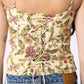 Floral top with thin straps worn by a person, with a plain background
