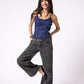 Woman wearing a blue tank top and gray wide-leg jeans on a white background