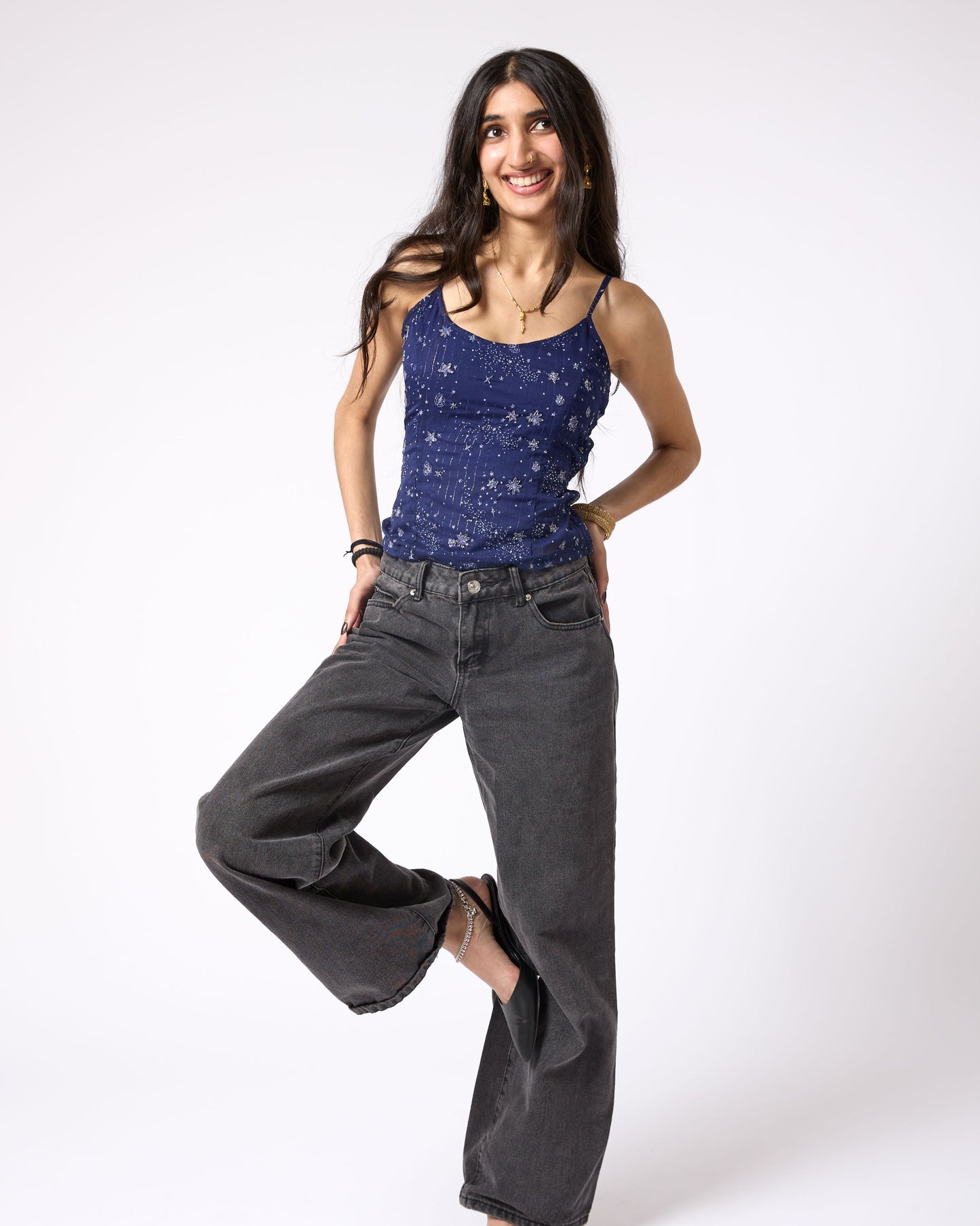 Woman wearing a blue tank top and gray wide-leg jeans on a white background