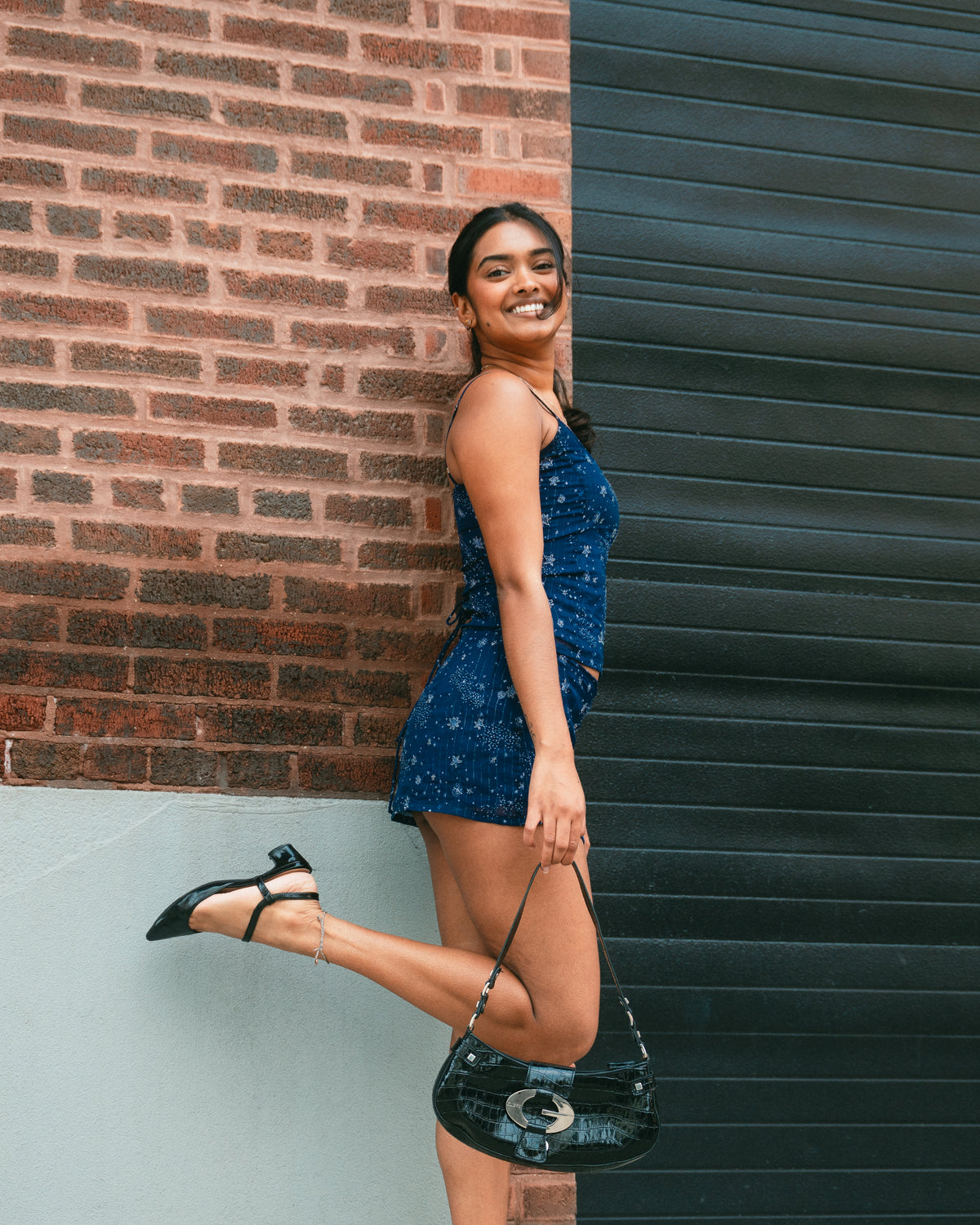 Woman in a blue dress standing against a brick wall