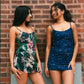 Two women wearing floral and navy blue swimsuits standing against a brick wall.